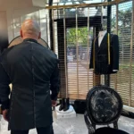 Sırt provasında müşteri arkadan görünüyor; siyah ceketin sırt ortası dikişi beyaz teyelle işaretlenmiş